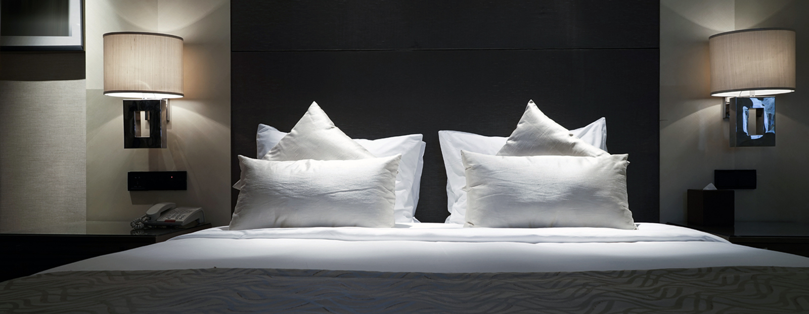 bed with several pillows and a bedside lamp