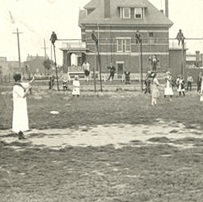Severeal people play a game with raquets and a net in a playground