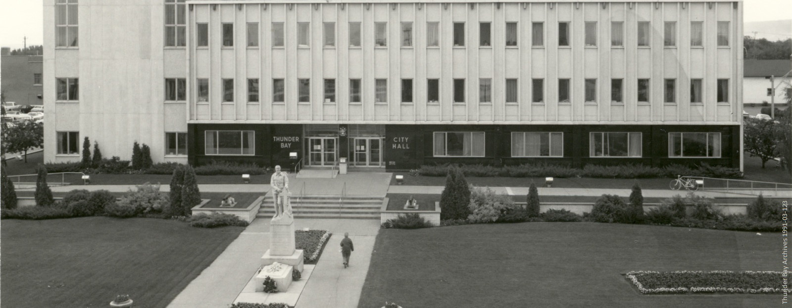 A large building with manicured lawn and bushes in front