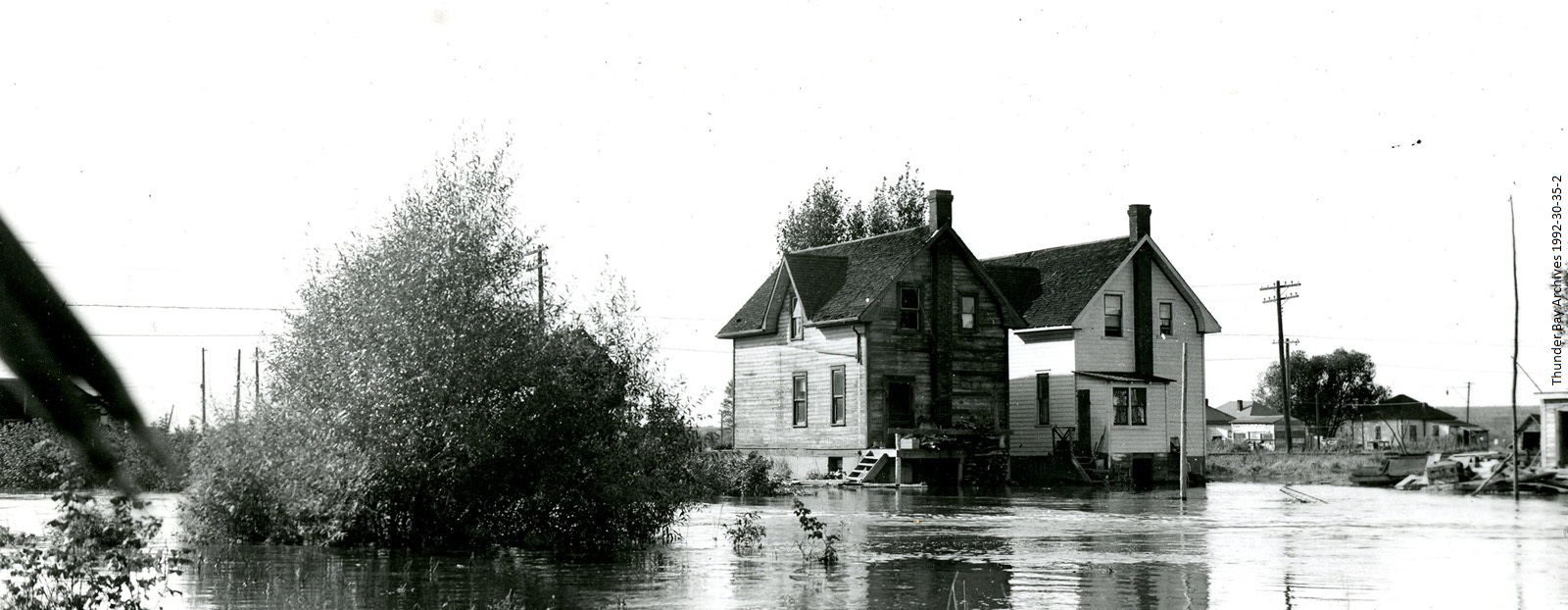 Two houses sitting in a field of water after a flood 