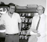 Two men stand in front of a vending machine 