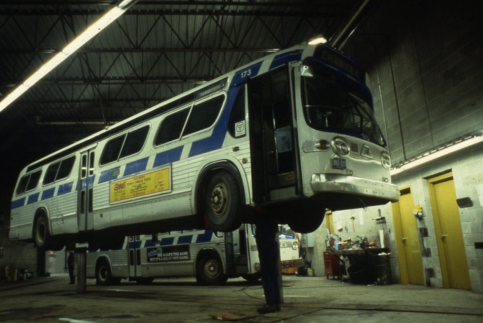 A bus hoisted in the air on two poles in a garage