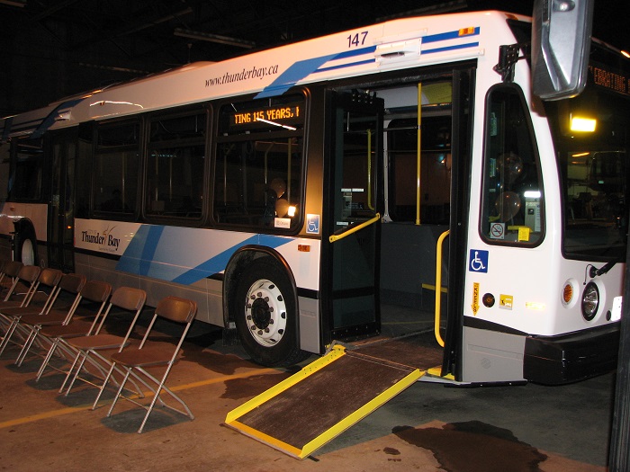 A bus sitting parked with an accesible ramp open and on the floor