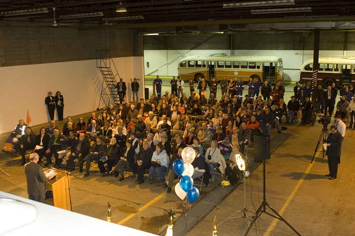 A crowd of people sitting in a room listening to speeches