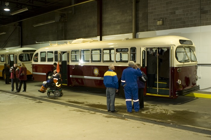 A group of people looking at a restored red and white trolley bus