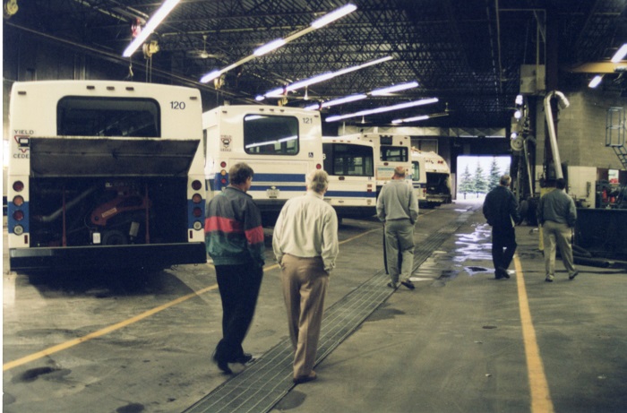 Buses lined up in a garage with one open at the back with engine exposed