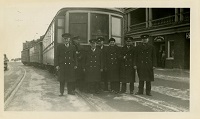 A group of men standing in front of a trolley car