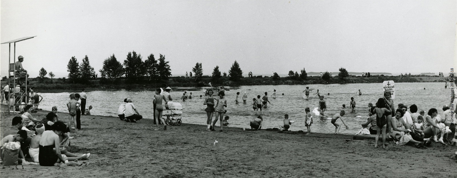 Groups of people play on the beach and in the water at a park