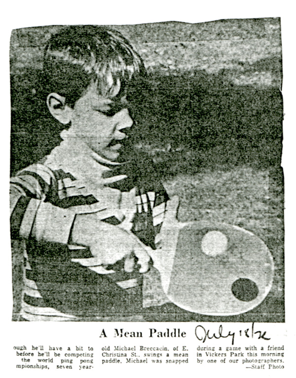 A young child holding a paddle in motion to hit a ball 