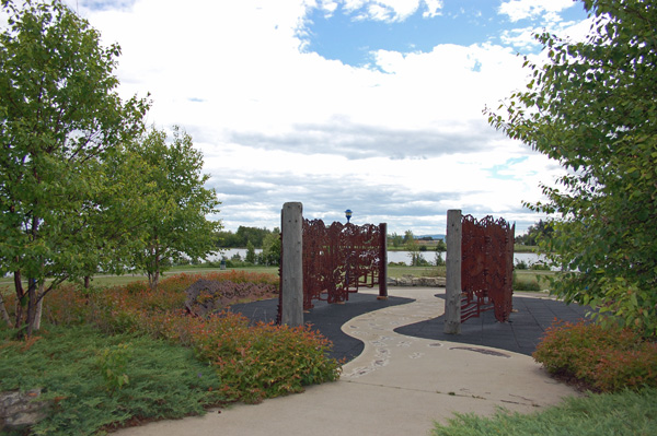 Two bronze fish sculptures framing a pathway among trees