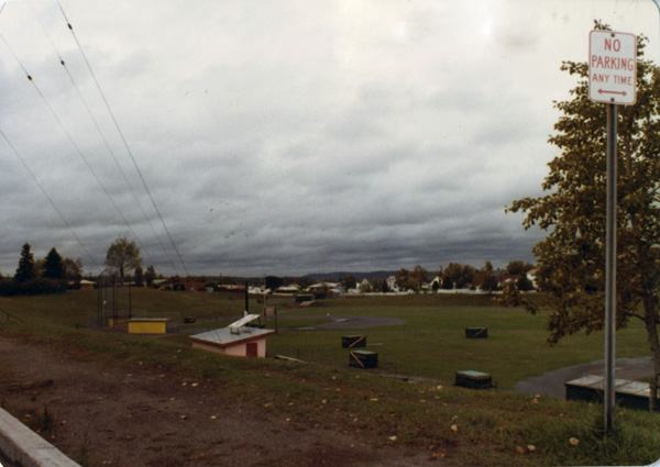 A baseball field with dugout with houses in the background