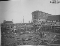 A building under construction with equipment and a hole in the ground