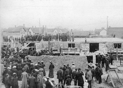 A group of people among construction equipment laying brick