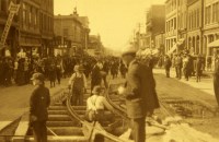 a crowd of people standing on railway tracks in a sepia photograph