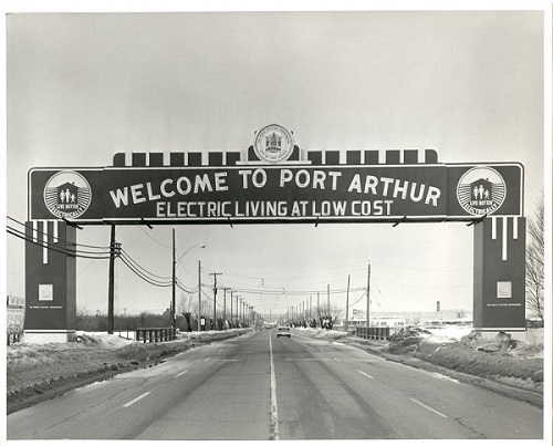 an arch over the highway into Port Arthur proclaims electric living at low cost
