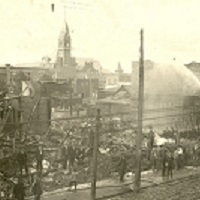Firemen spraying a building with a hose on a downtown street