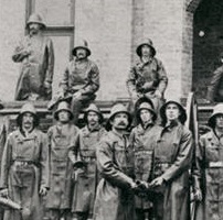 A group of firemen standing in front of a building 