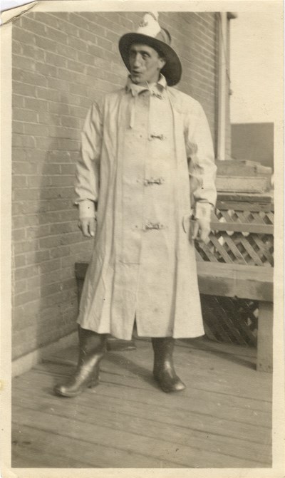 A man standing dressed in firefighting equipment wearing a hat