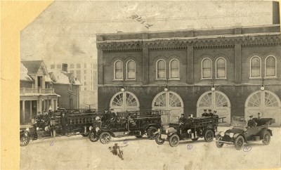 A grouping of fire trucks located outside of a brick building