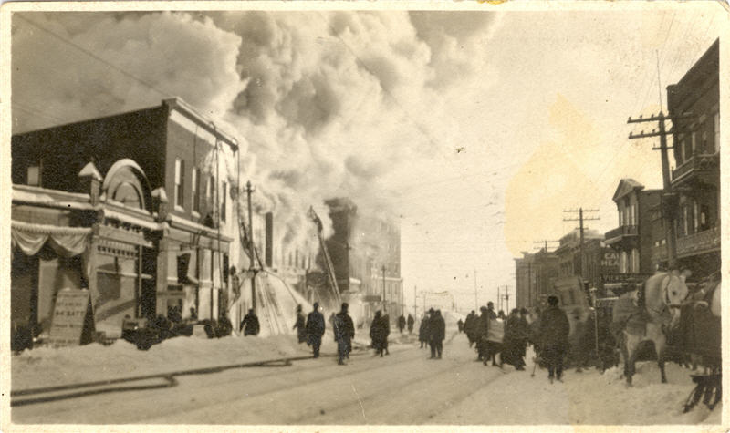 A photo of firefighters putting out a fire on a street with billowing smoke