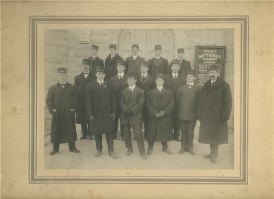 A group of men standing together wearing suits and hats 