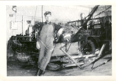 A man leaning back against a fire truck in a black and white photo