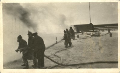 A group of firemen in a black and white photo putting out a fire 