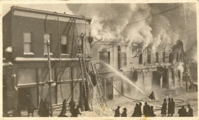 A group of firemen putting out a fire with trucks and hoses