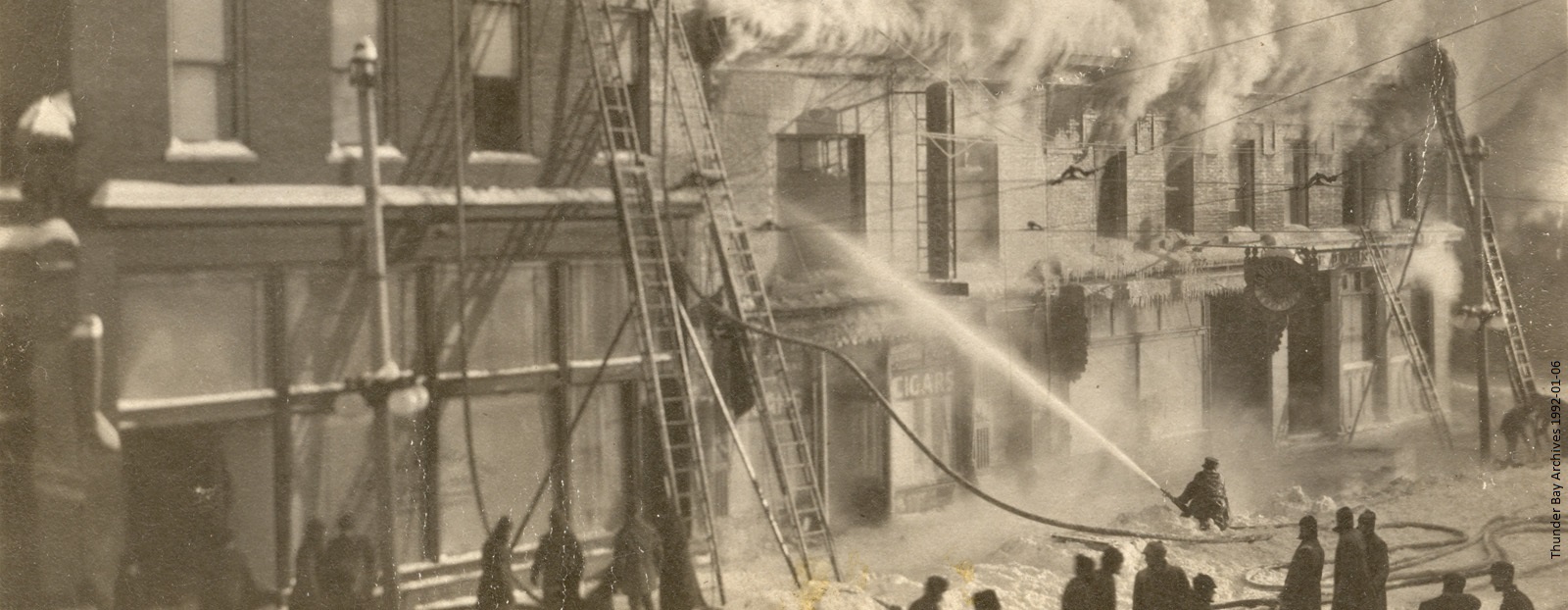 A group of firefighters extinguishing a fire using ladders and hose