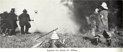 A group of firefighters standing looking at a fire 