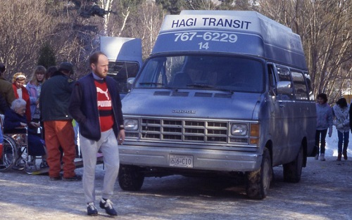 A person standing in front of a blue and white Handi-Transit van 