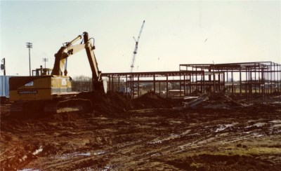 A construction machine digging a hole, as a metal frame is in the background