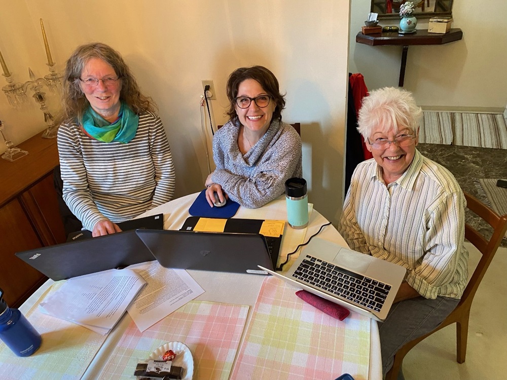 Lynda McKeown sitting at table with laptops and unidentified individuals