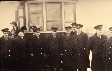 a group of railway conductors standing in front of a trolley car