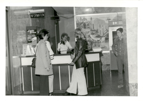 Two women standing in front of a desk marked as information