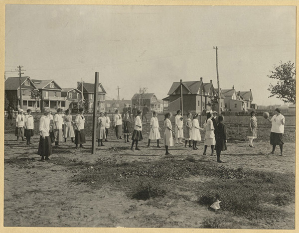 Girls playing volleyball on an outdoor court. 