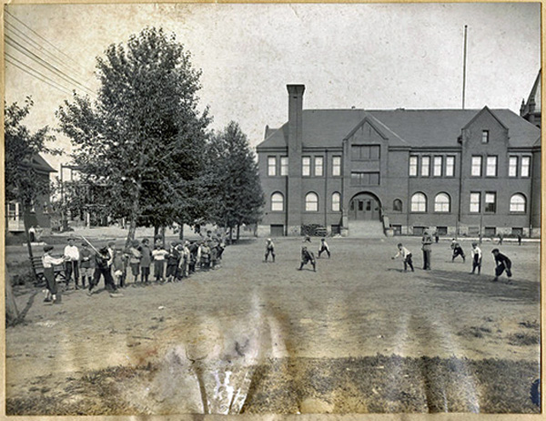 Boys playing dodgeball in front of a school