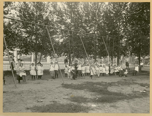 young girls on and near swings under the trees