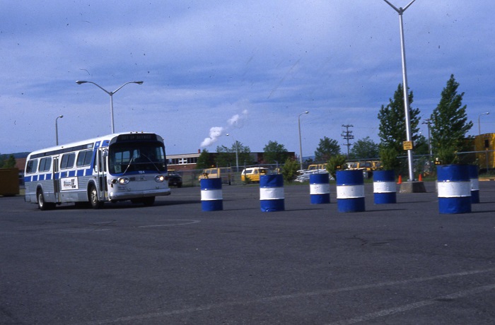 A bus driving towards blue and white striped barrels to test agility