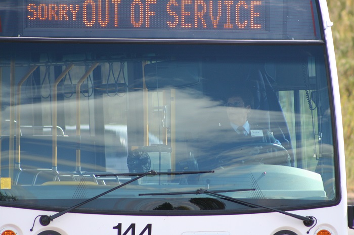 A transit driver sitting in a bus with a 'Sorry out of Service' sign
