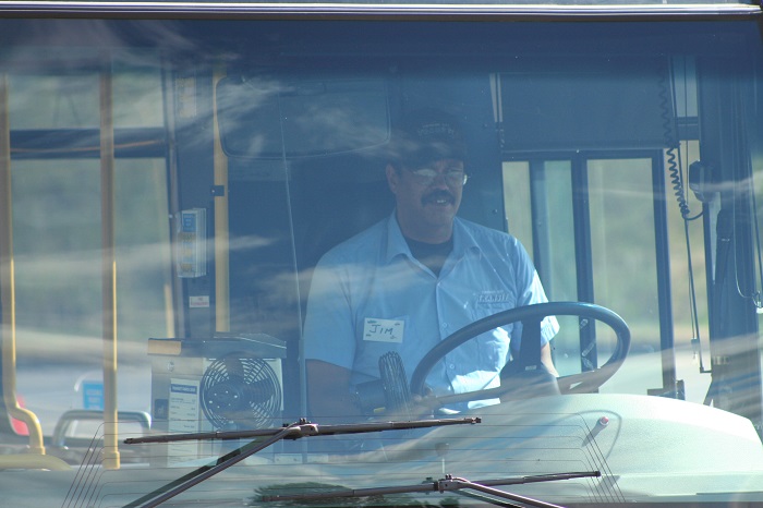 A transit driver sitting smiling on a bus