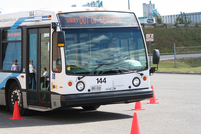 A bus with an out of service sign navigating through orange pylons