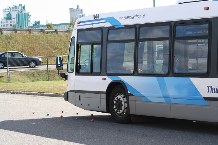 A bus driving forward onto a road with small balls lined up in front 