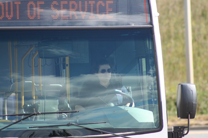 A bus driver sitting waiting on a bus that says out of service