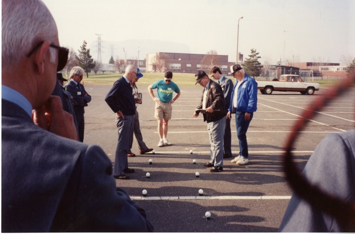 A group of people assessing the location of small balls on the ground