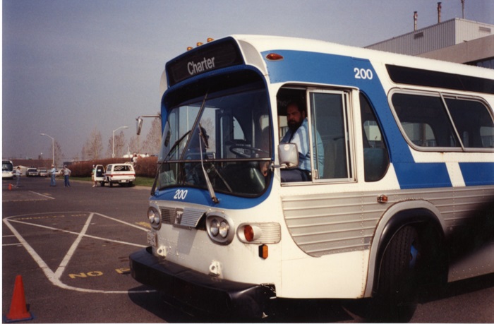 A transit driver sitting and looking out the window of the bus he is driving