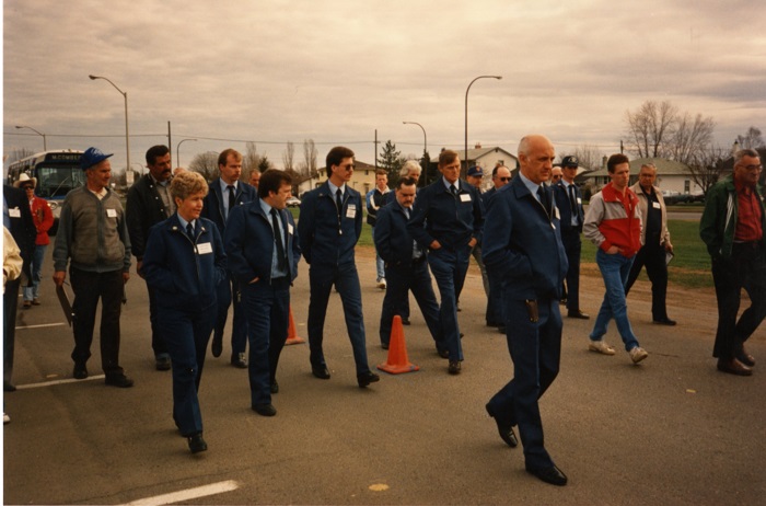 A group of transit drivers and others walking through an empty parking lot