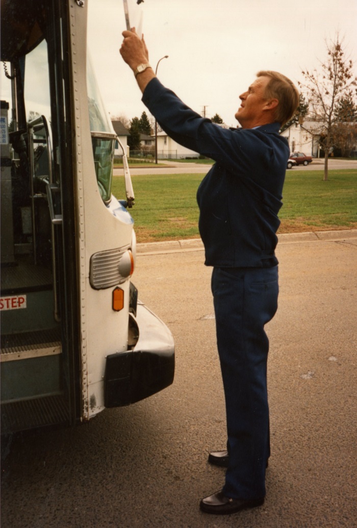 A man showing someone sitting on a bus a sign on his clipboard