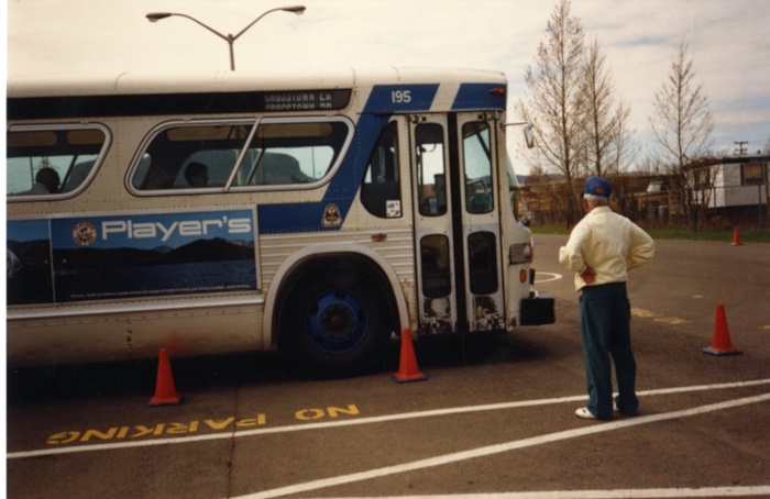 A man standing looking at the side of a bus in a parking lot