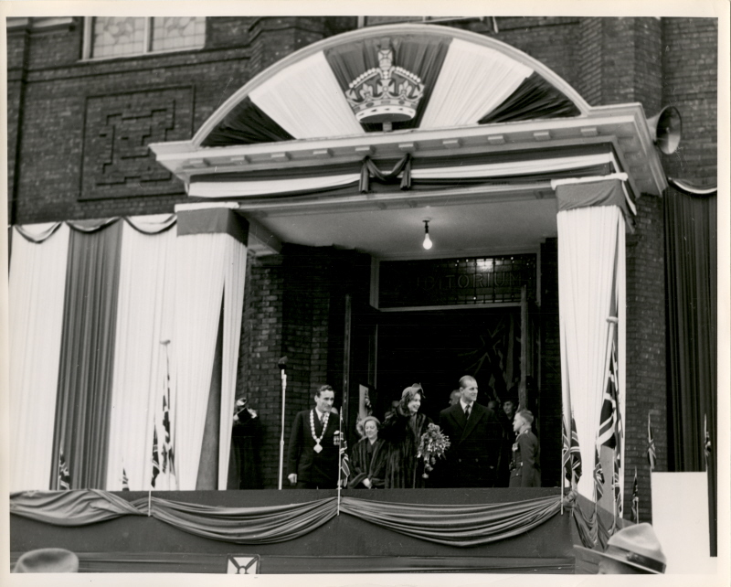 A group of people standing outside on a decorated balcony 